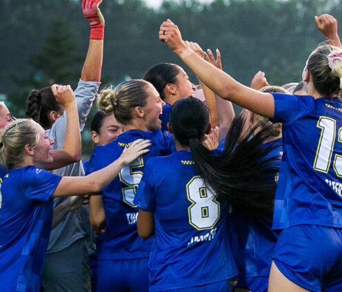 group of sdsu women's soccer players celebrating in a huddle
