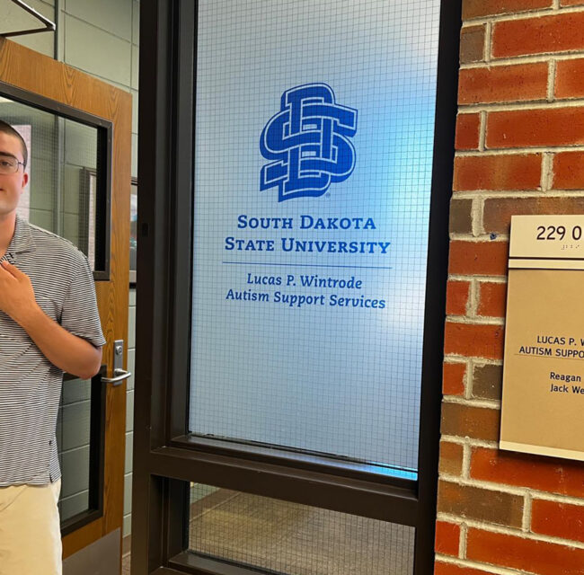 Lucas Wintrode standing in front of the Lucas P. Wintrode Autism Support Services Office.