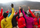 Dick Deming high-fiving others in a group at the base of a mountain
