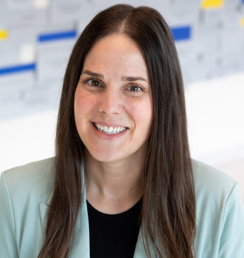 Headshot photo of Brandi Haraldson with a grey, blue, and yellow blurred background