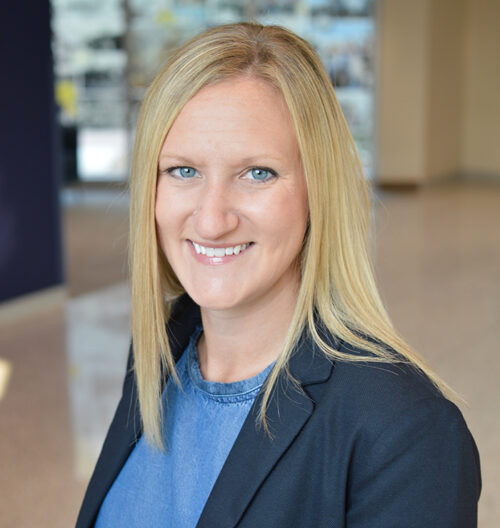 Professional headshot of Carolyn Poss, with blurred background.