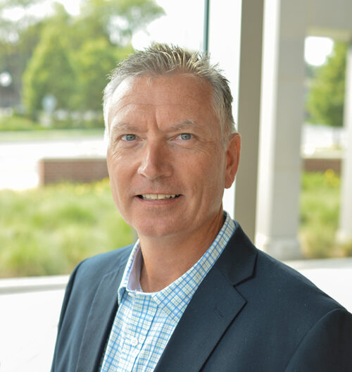 Professional headshot of Tim Dwire, with a green blurred background.