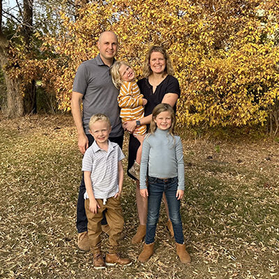 Erin Glidden and her husband Tyler with their three kids with a fall scenic background