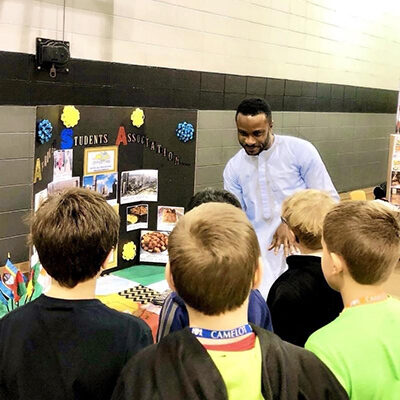 Sean Edeki presenting on African culture to a group of middle school students during Cultural Appreciation Day.