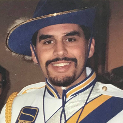 Close up photo of Kevin Kessler when he was a SDSU student and member of the Pride of the Dakotas, smiling in his uniform.