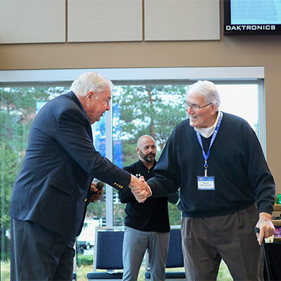 Jerry Lohr shaking Frank Kurtenbach's hand, both smiling.