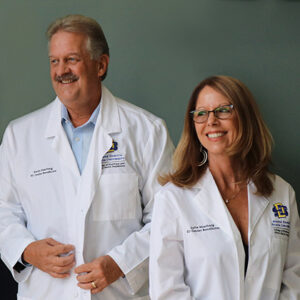Photo of Kevin and Lorie Haarberg smiling, wearing pharmacy whites that were given to them as gifts from the College.