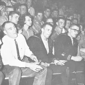 Coach Warren Williamson, Dave Kinney, and Kurtenbach watch with mixed emotions as the action on the wrestling mat gets intense.