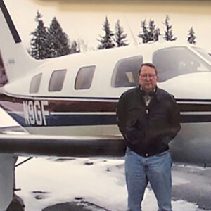 Al Tuntland posing in front of an airplane on a snowy, cold day.