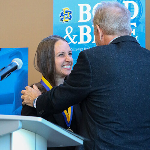 Dr. Carie Green smiles while Tate Profilet places the medallion around her neck.