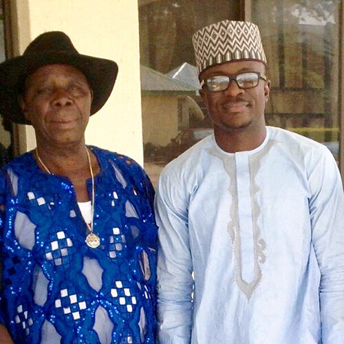 Sean Edeki, in traditional African clothing, standing next to his father.