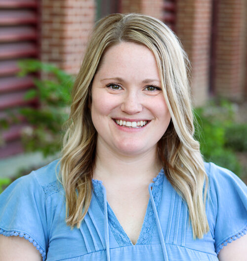 Professional headshot of Jillian with a blurred brick background