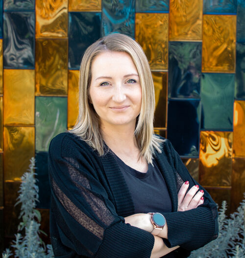 Professional headshot of Natasha Smith in front of a blue and gold background.