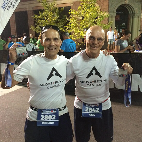 Dick Deming and another male hold up medals after a running competition.