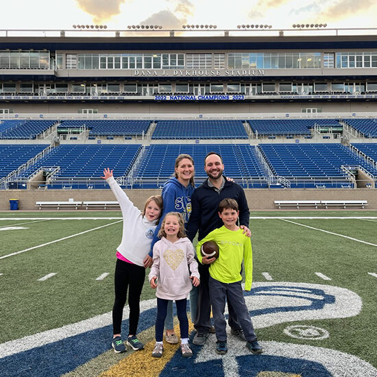 Rachel and her family stand on the 50 yard line of the Dana J Dykhouse Stadium at South Dakota State University