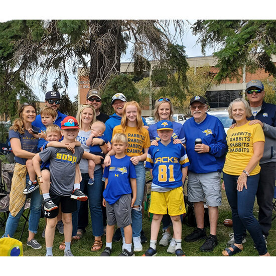 Carolyn Poss and 10+ members of her extended family, smiling for a photo all dressed in Jackrabbit gear.