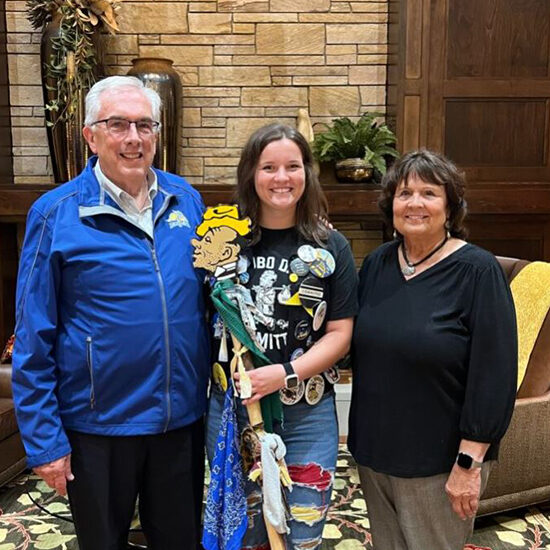 Marissa smiles while posing in between President Dunn and Jane Dunn.