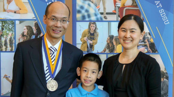 Dr. Zhiguang (Gerald) Wang posing and smiling with his wife and young son.