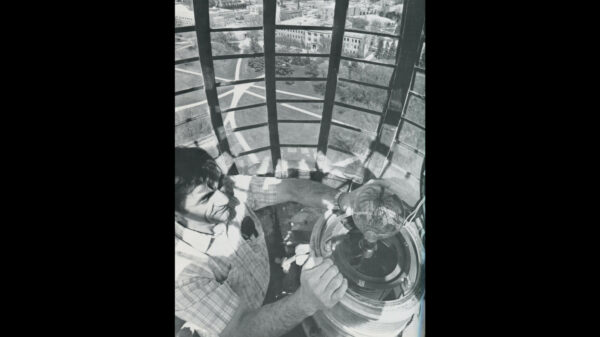 Man in the top globe portion of the Campanile, changing the beacon light.