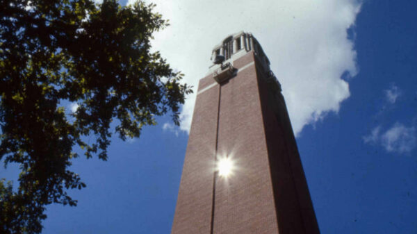 Photo of Campanile, looking up from the ground. The sun is reflecting off an upper window, creating a sun flare.