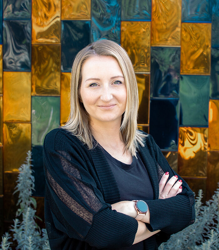 Professional headshot of Natasha Smith in front of a blue and gold background.