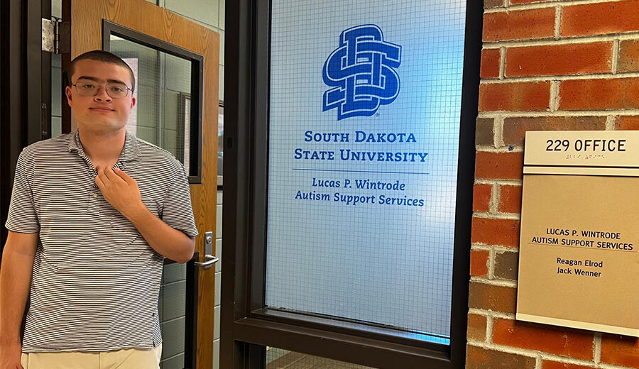 Lucas Wintrode standing in front of the Lucas P. Wintrode Autism Support Services Office.