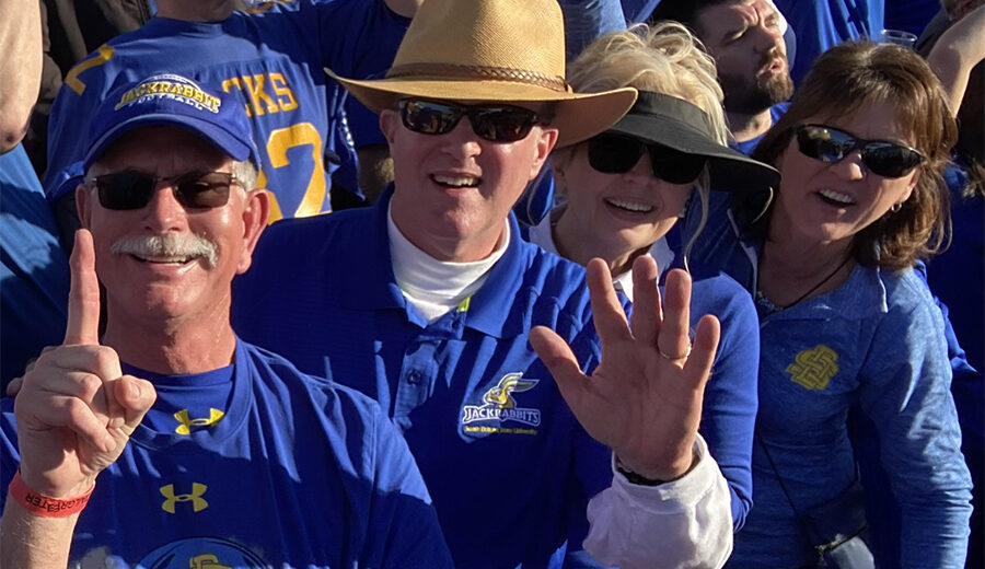 Craig Carson and Dave Schaefer smile with their wives at the FCS Championship game in Frisco, TX.